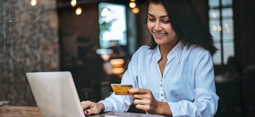 Cliente sorridente utilizando cartão e notebook para realizar compra online